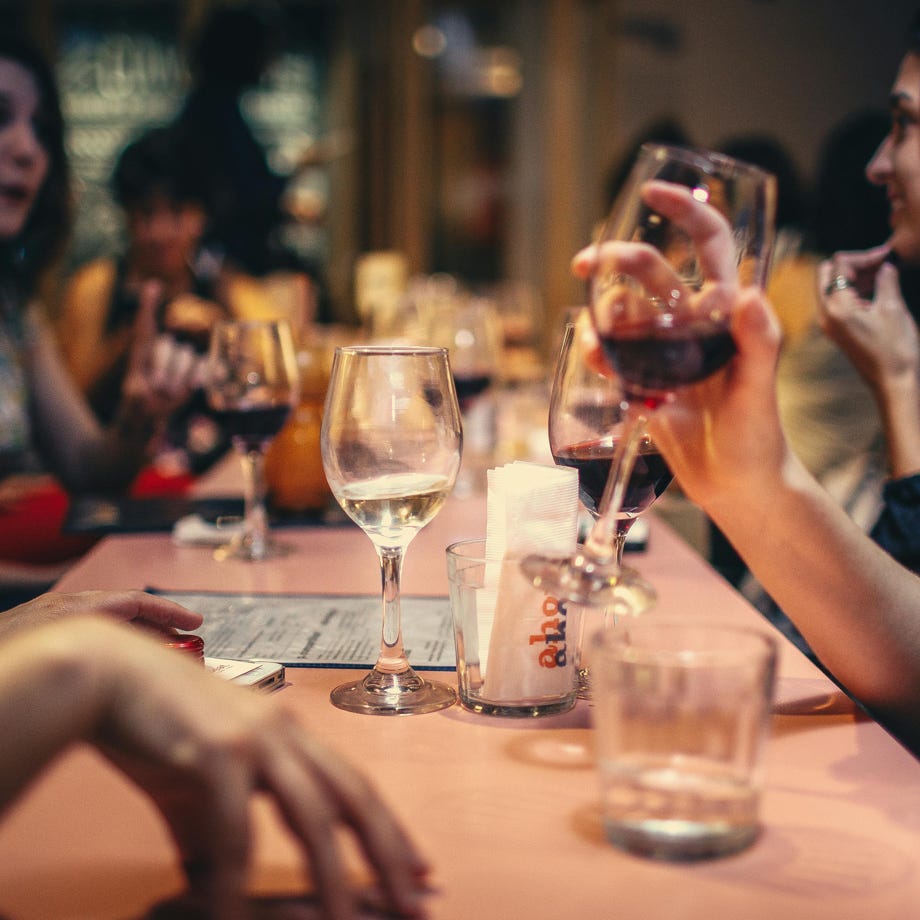 An elegant hand holding a wine glass beside a candlestick on a refined table setting.